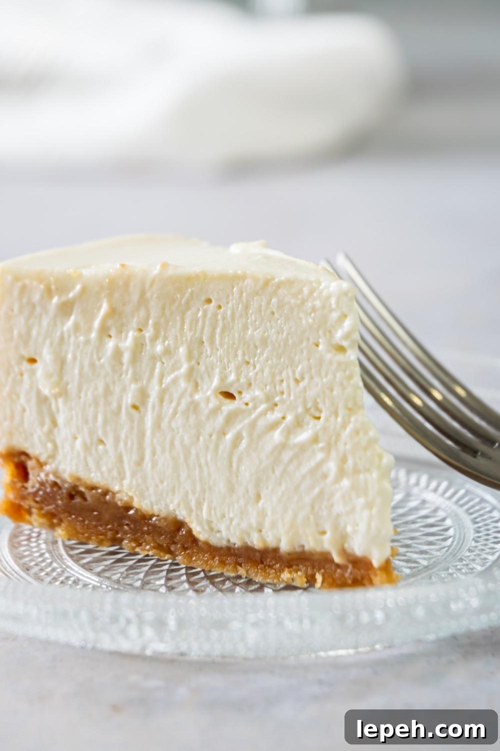 A slice of Philadelphia No Bake Cheesecake on a serving plate. A fork sits next to it.