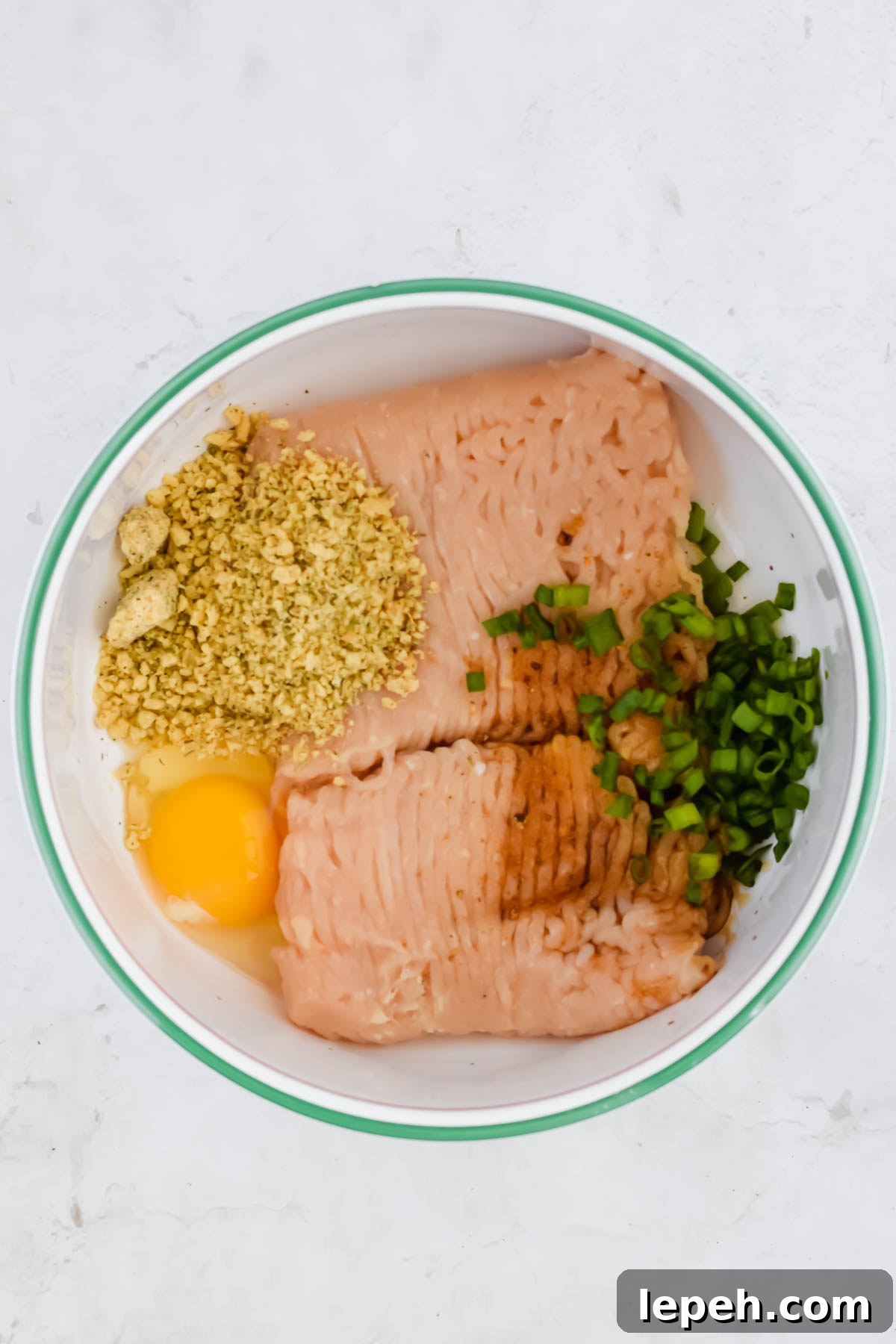 asian chicken meatball ingredients unmixed in white bowl on white background.