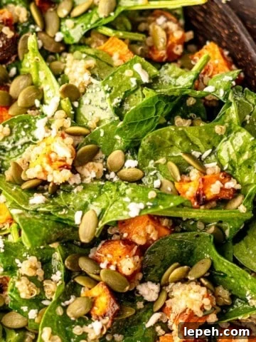 A spinach and sweet potato salad with salad spoons.