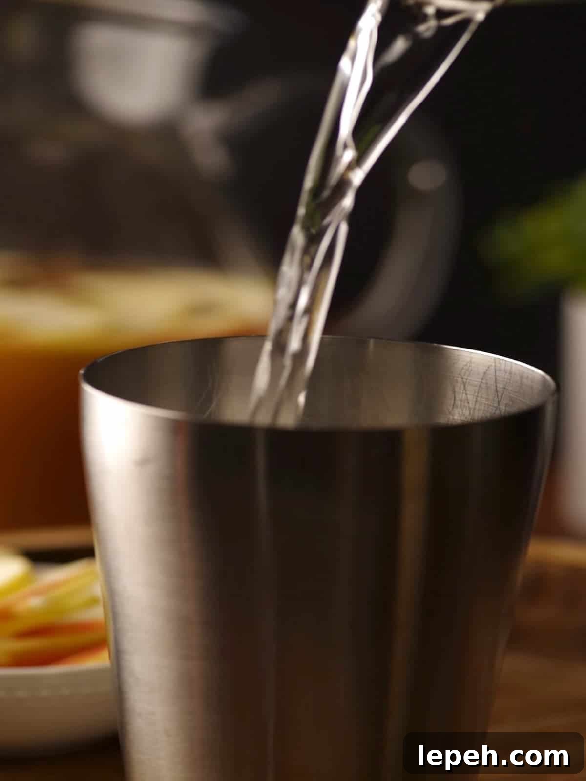 Tequila being poured into a cocktail shaker.