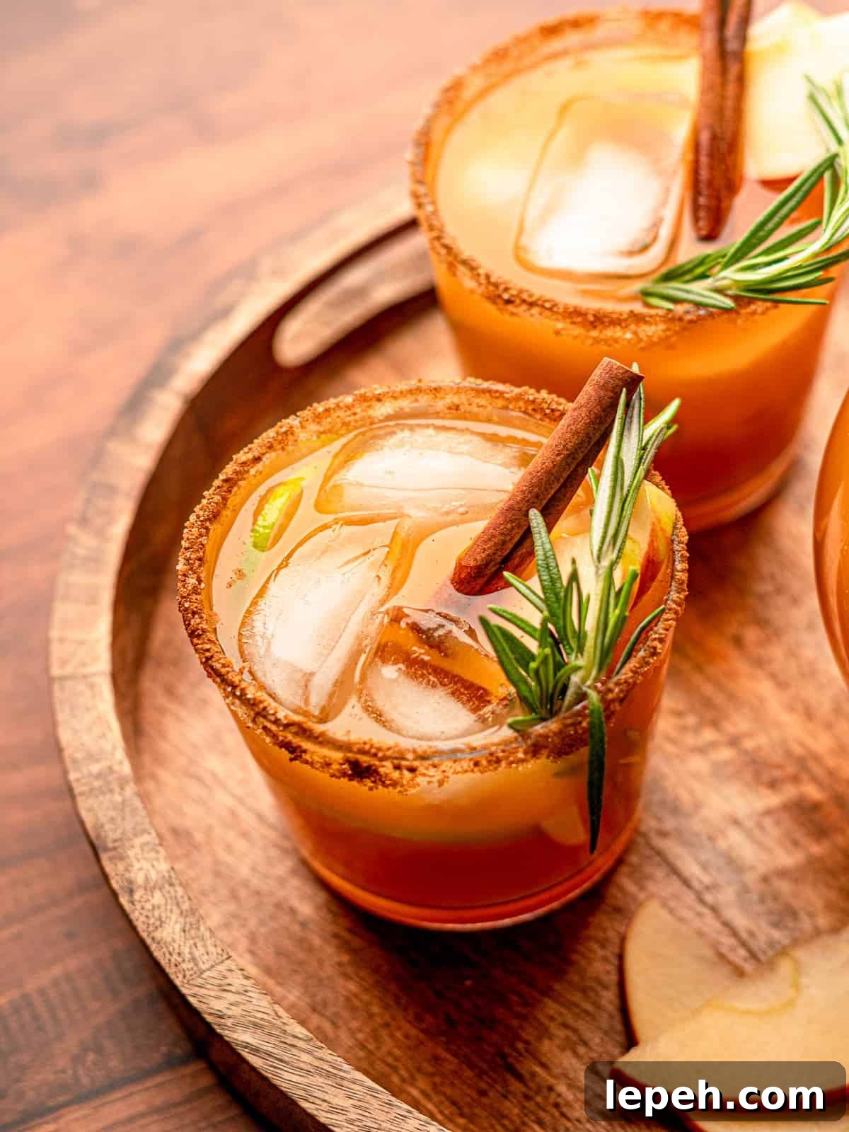 Two cocktails garnished with rosemary on a tray.