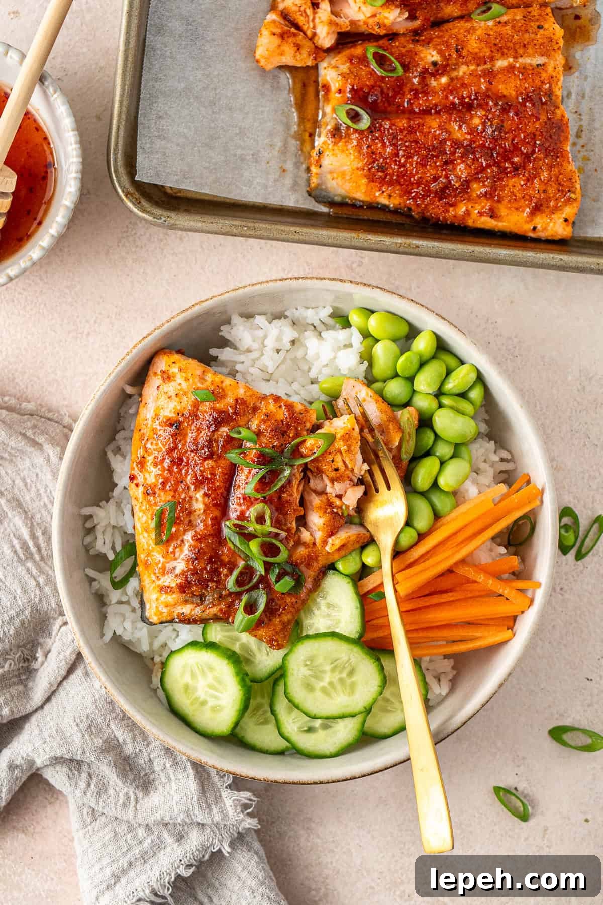 A fork in a rice bowl with hot honey salmon.