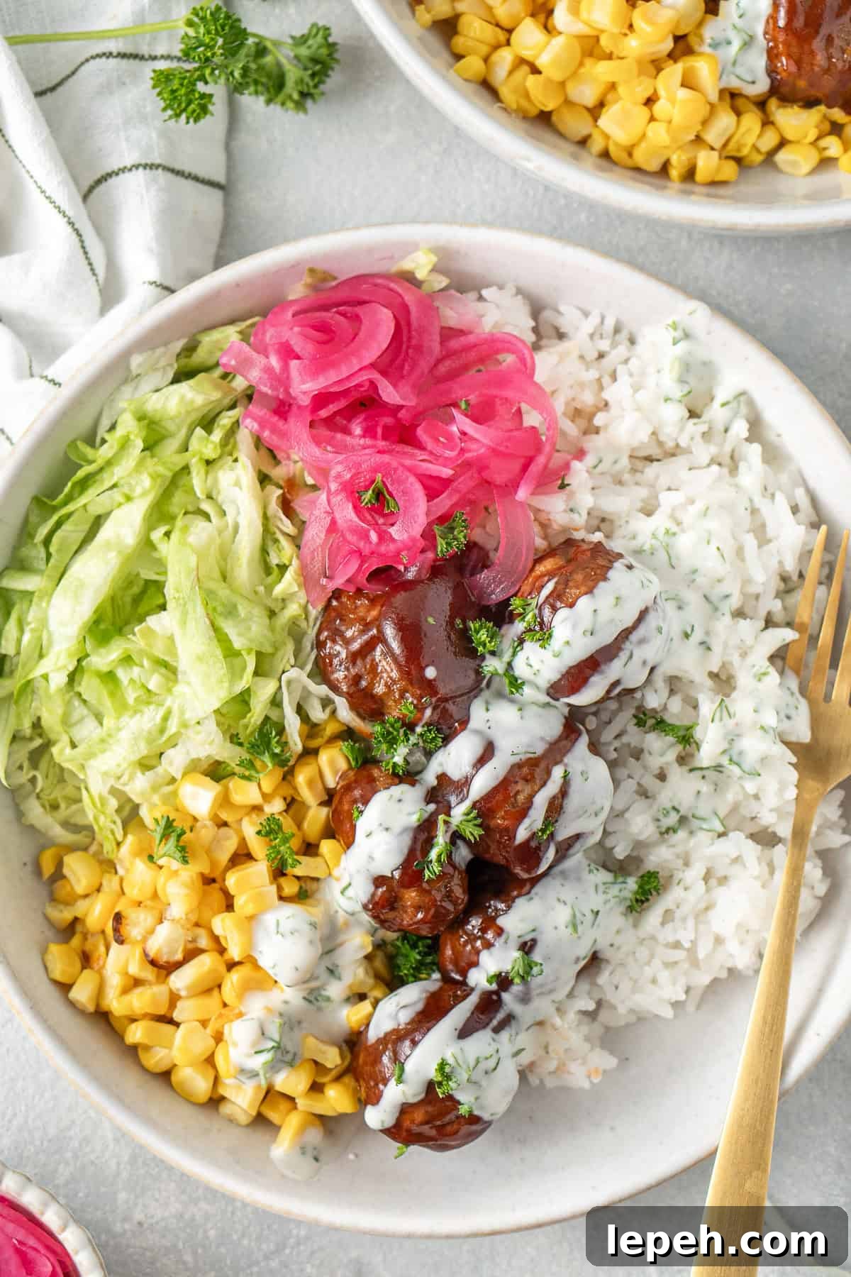 Rice bowl with BBQ meatballs, corn, lettuce and pickled onions.