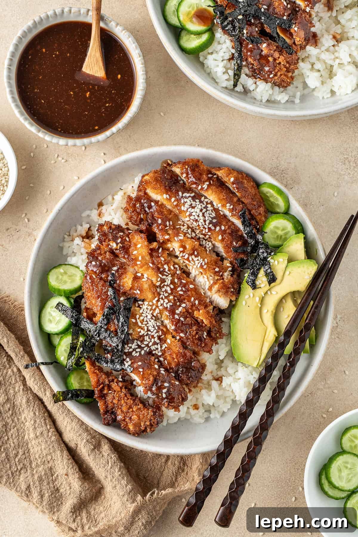 Chicken katsu in a bowl with rice and chopsticks.