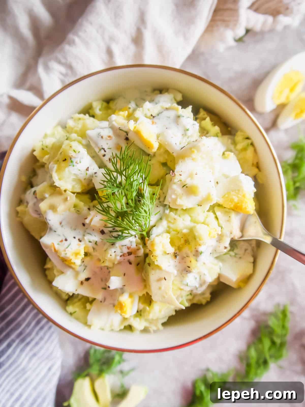 Avocado potato salad recipe in a bowl with a spoon in it.