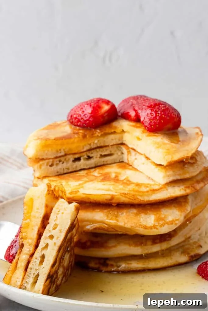 Gluten free pancakes in a stack with a piece cut out and strawberries