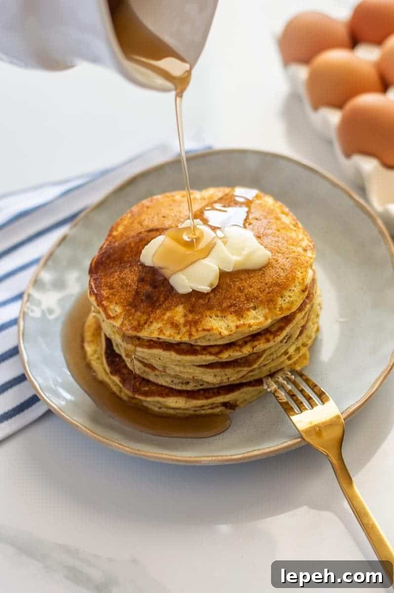 Short stack of pancakes with butter and syrup being drizzled on them