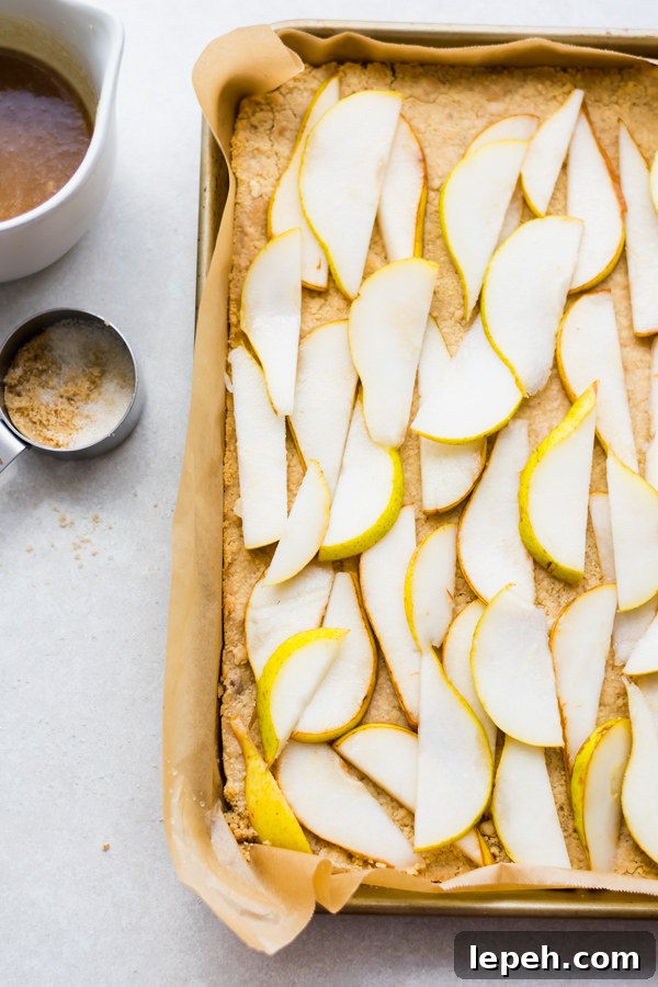 Sliced pears on dough in a tray.