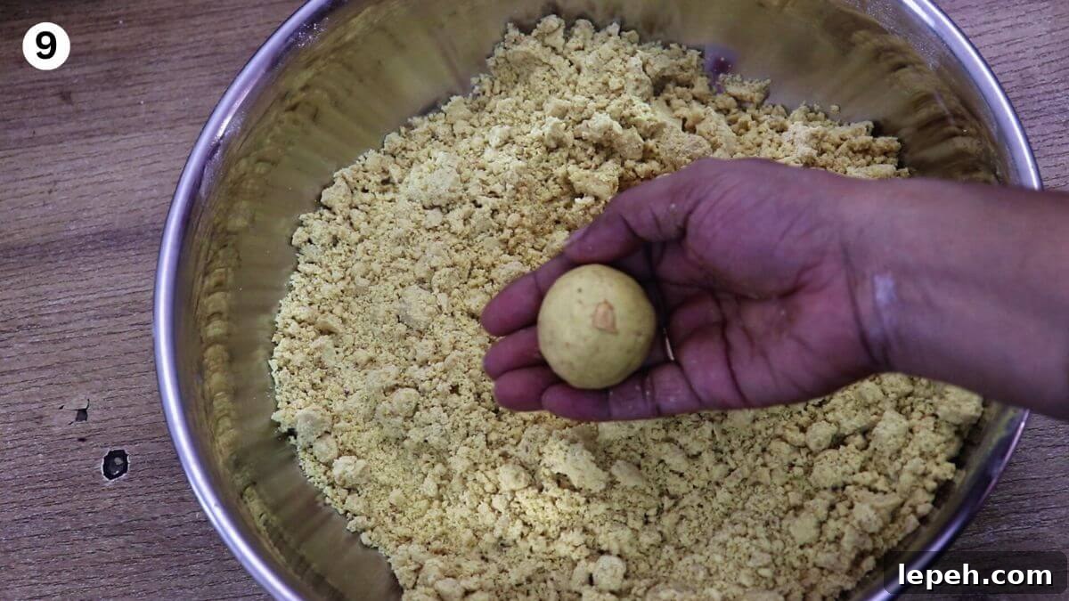 shaping a besan ladoo from the mixture, with one ladoo held in hand.