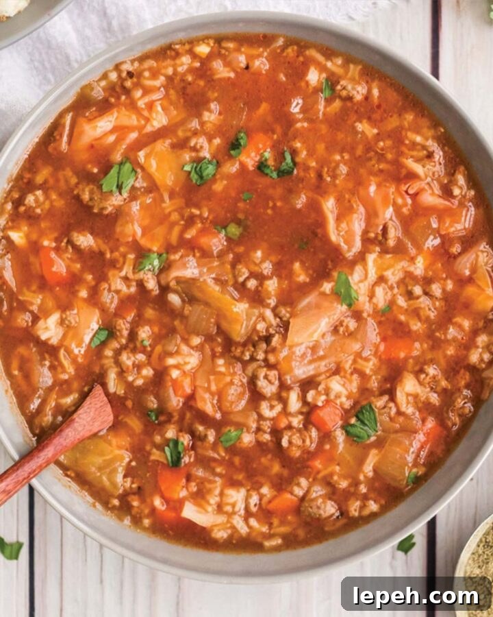 Pot of slow cooker cabbage roll soup served on the table with a wooden spoon.