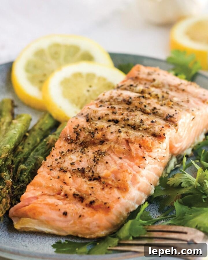 Grilled salmon served up on a plate with lemon slices.