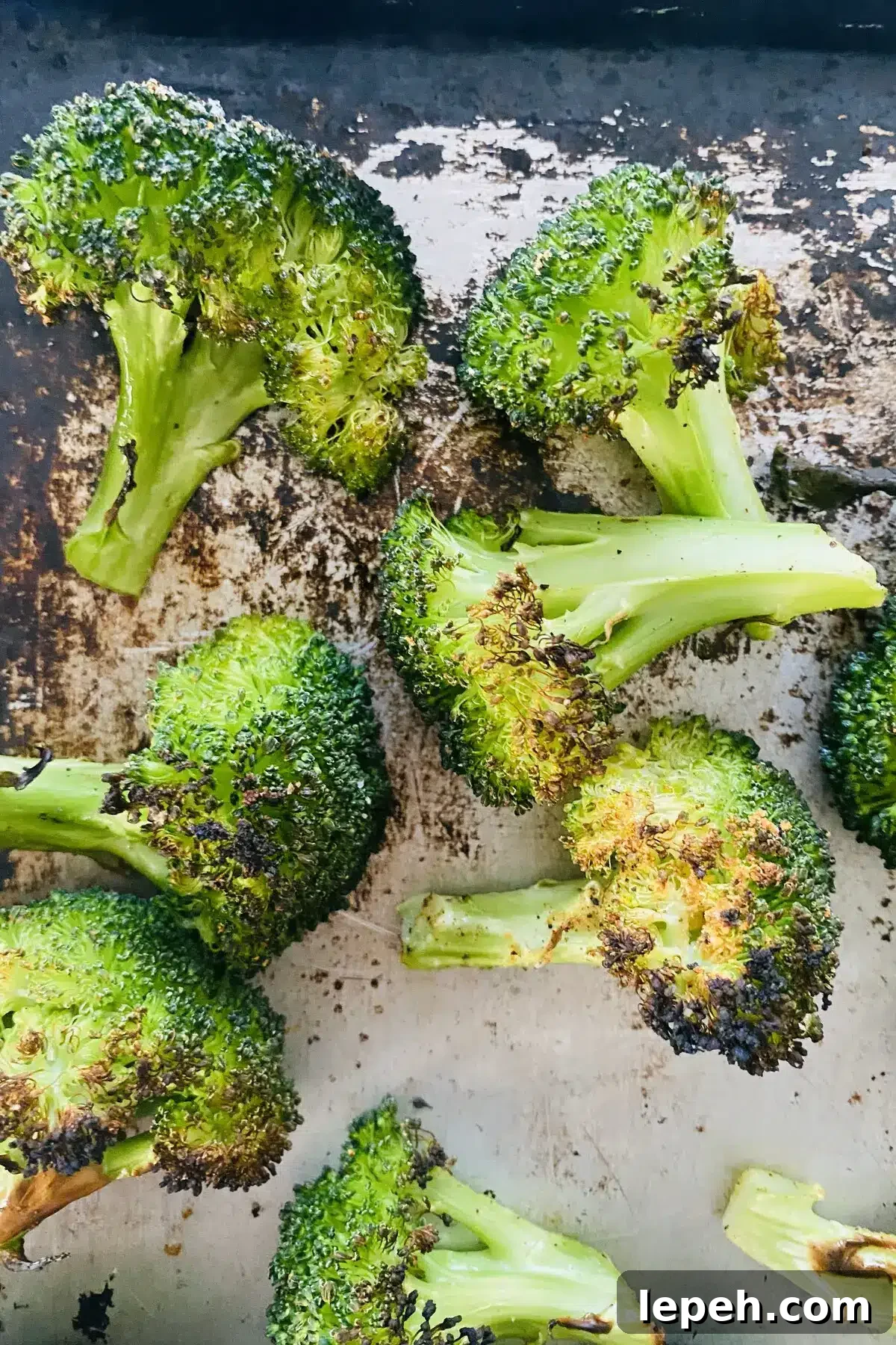closeup of broiled broccoli on a baking sheet.