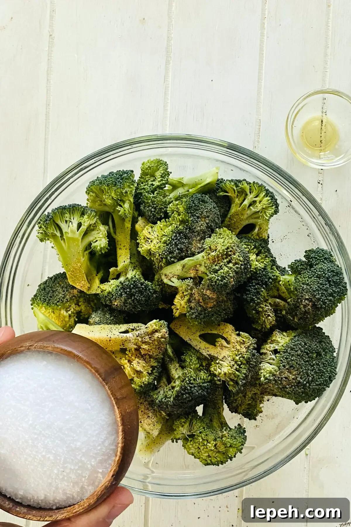 adding kosher salt to raw broccoli.