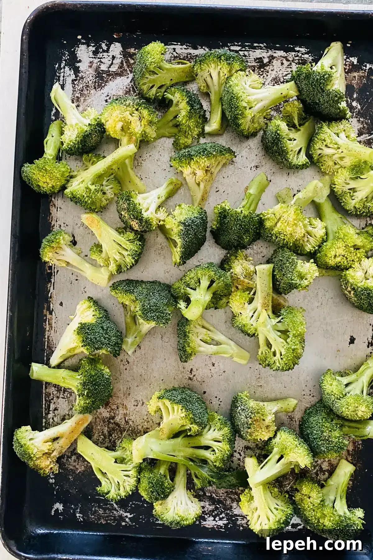raw broccoli seasoned and on a baking sheet.