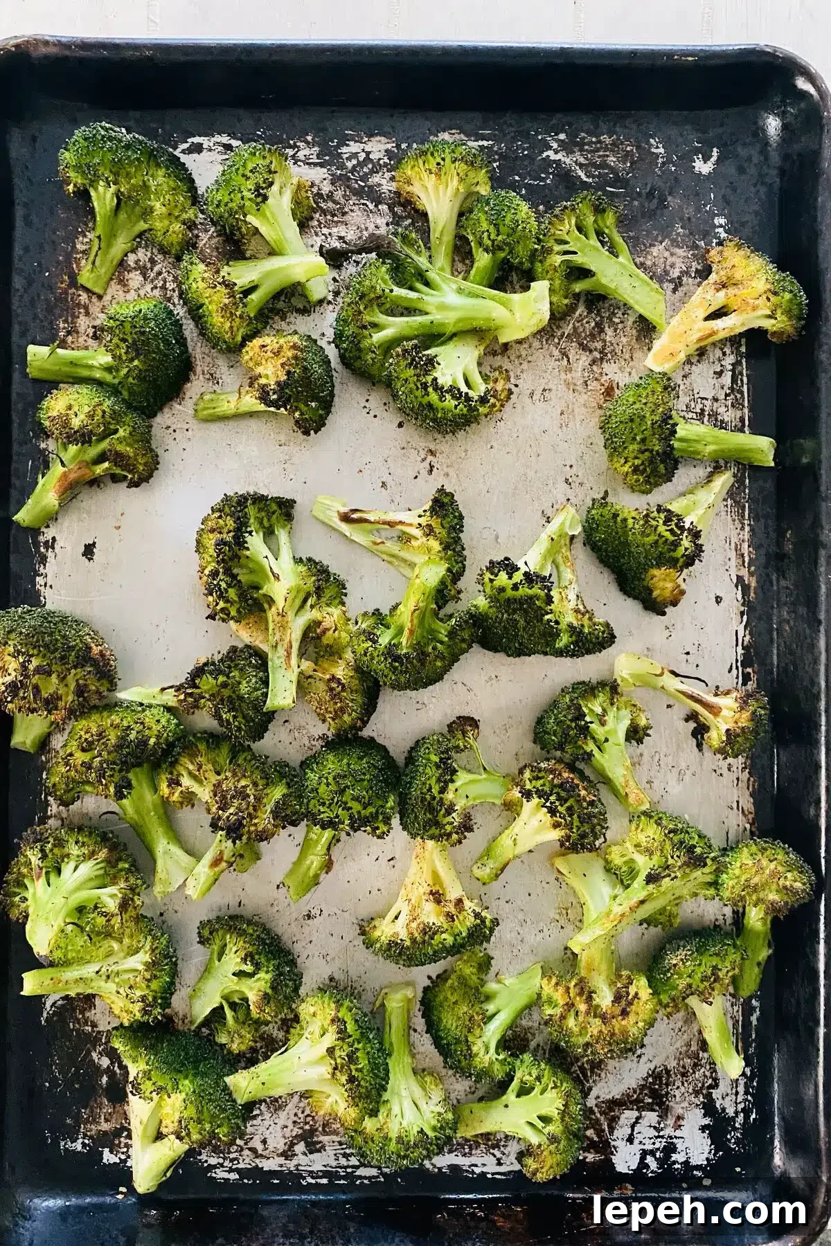 broiled broccoli recipe with broccoli on a sheet pan.