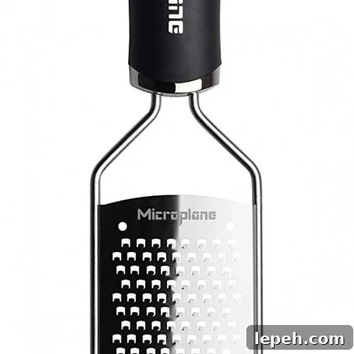 A stainless steel handheld grater with a black handle