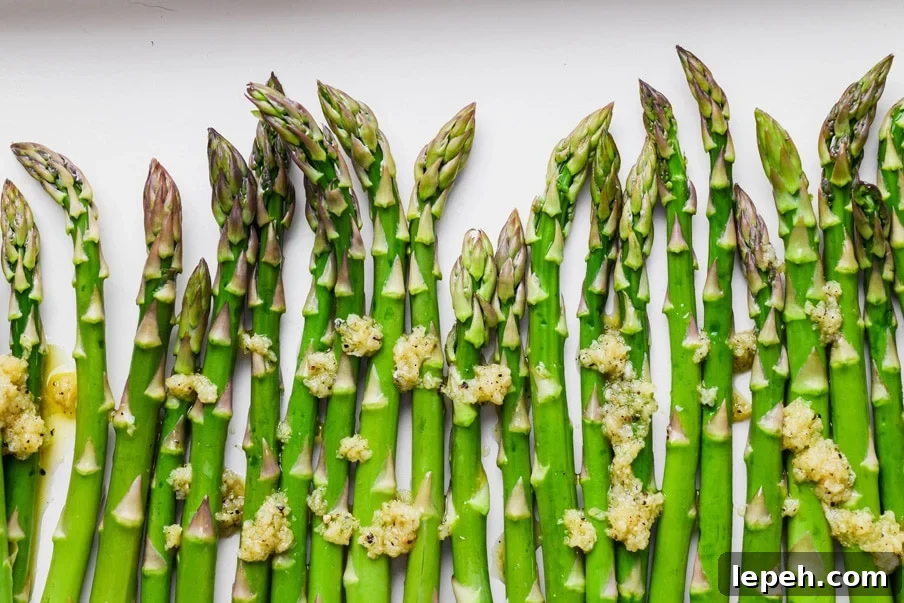 Landscape style overhead image of raw asparagus spears drizzled with garlic olive oil mixture. 