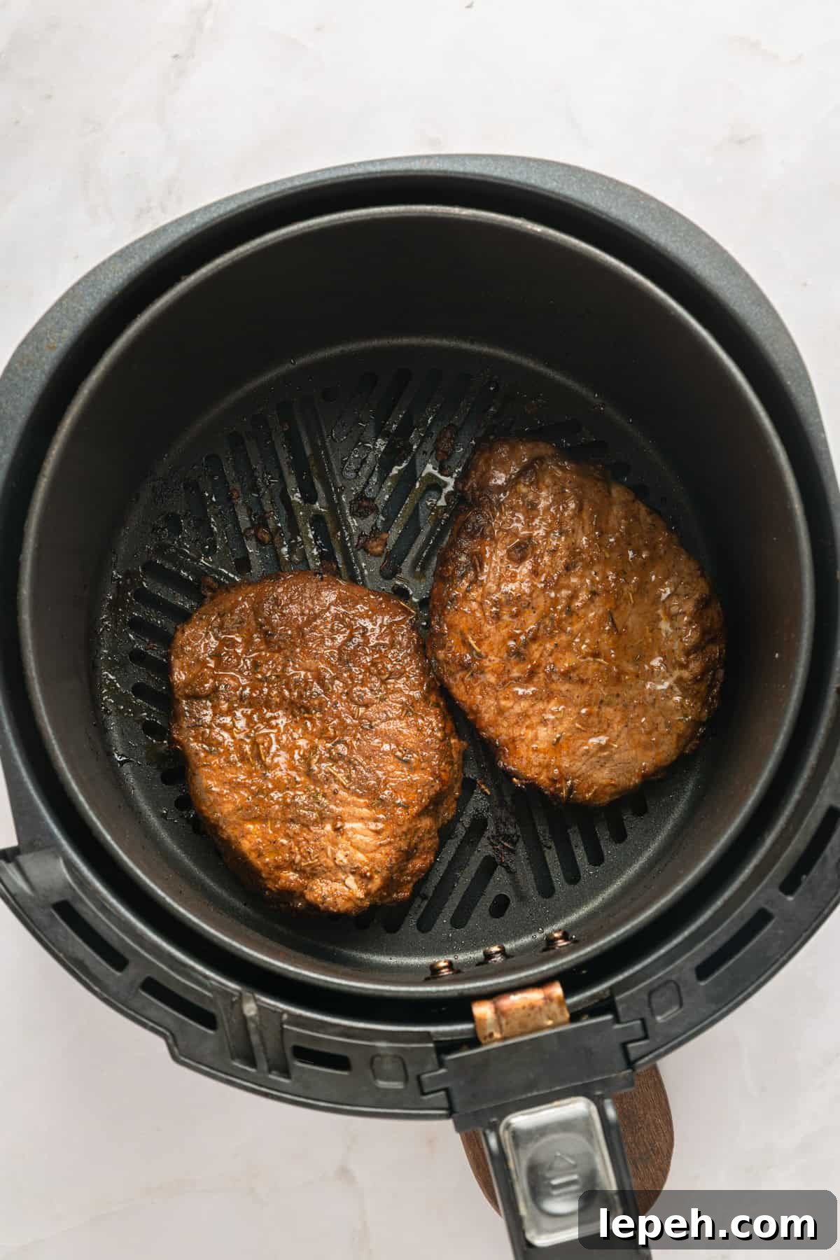 Boneless marinated pork chops cooked on one side in the air fryer basket.