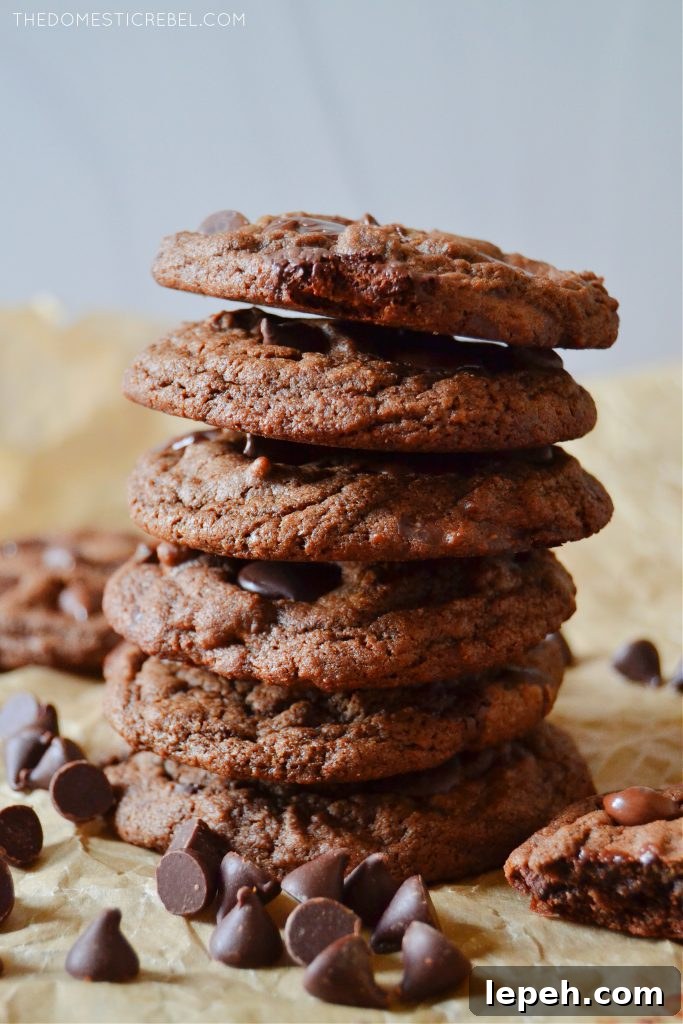 tall stack of chocolate chocolate chip cookies on parchment with choco chips