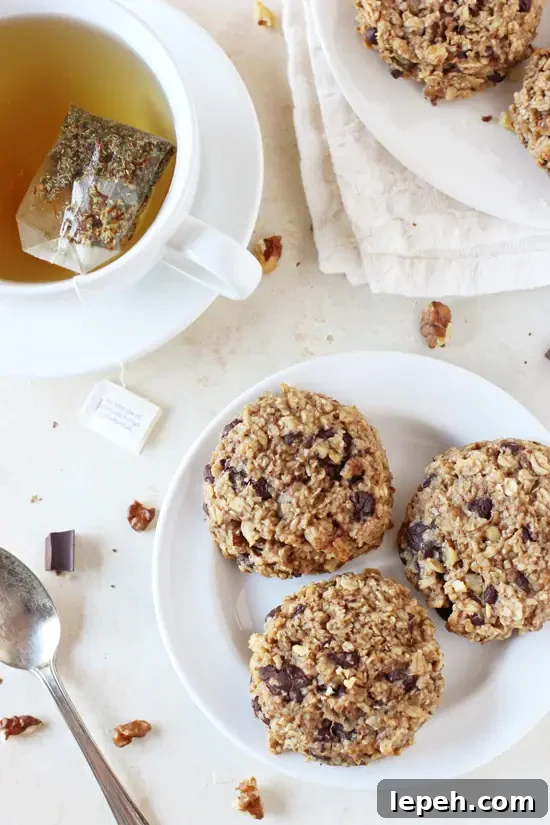 A white plate with three Banana Bread Breakfast Cookies with a cup of tea to the side.