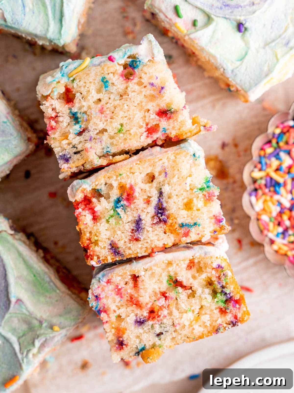 Three slices of rainbow sprinkle cake laying on their sides.