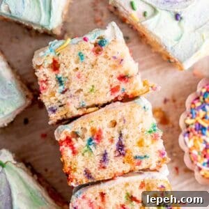 Slices of a rainbow sprinkle cake with vanilla buttercream frosting.