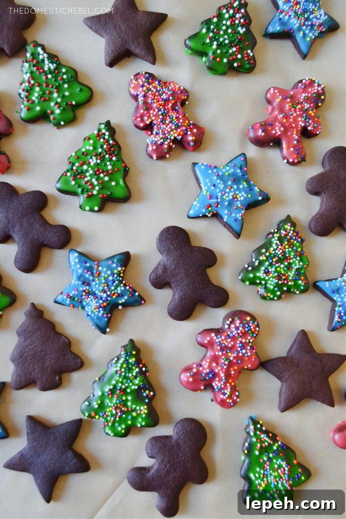 an assortment of frosted and unfrosted chocolate sugar cookies on a brown piece of parchment