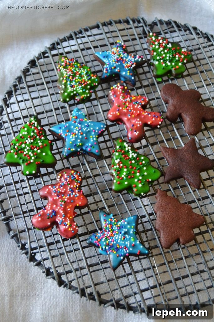 an assortment of chocolate sugar cookies, some frosted and some not, on a black wire rack