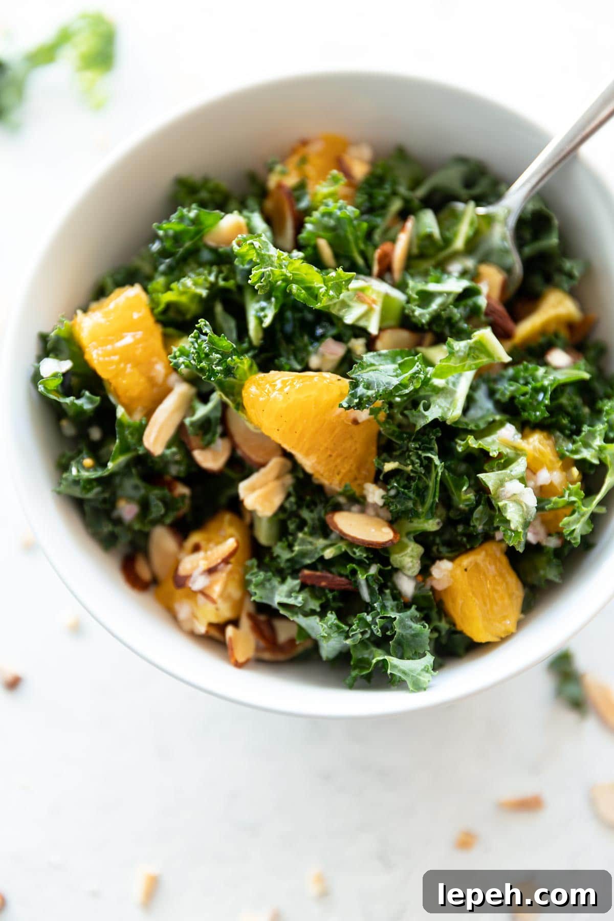 White bowl filled with kale and sliced oranges.