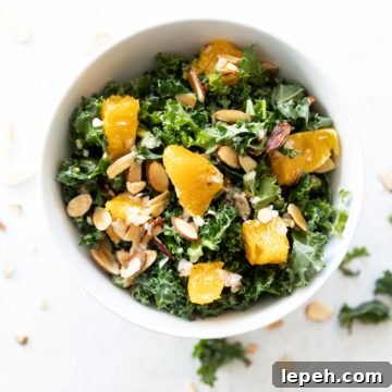 A bowl of orange and kale salad on white table.