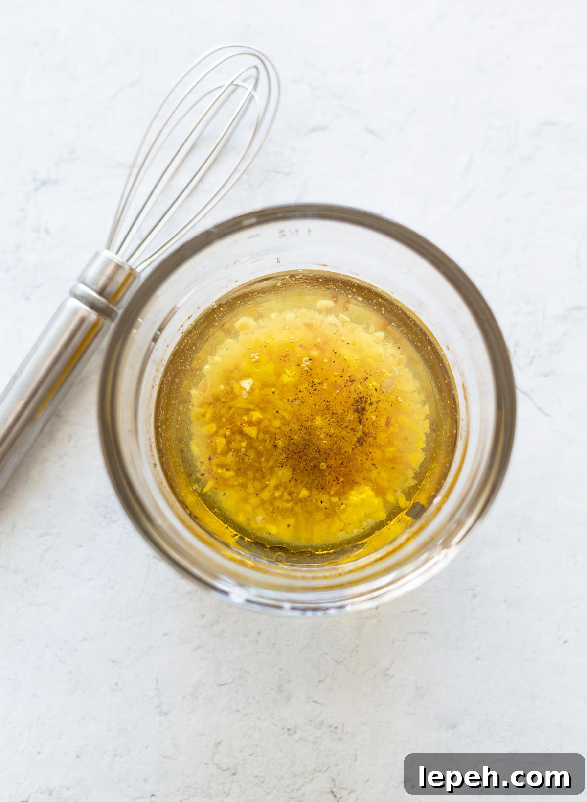 Ingredients for citrus vinaigrette dressing in a bowl, whisk on table.