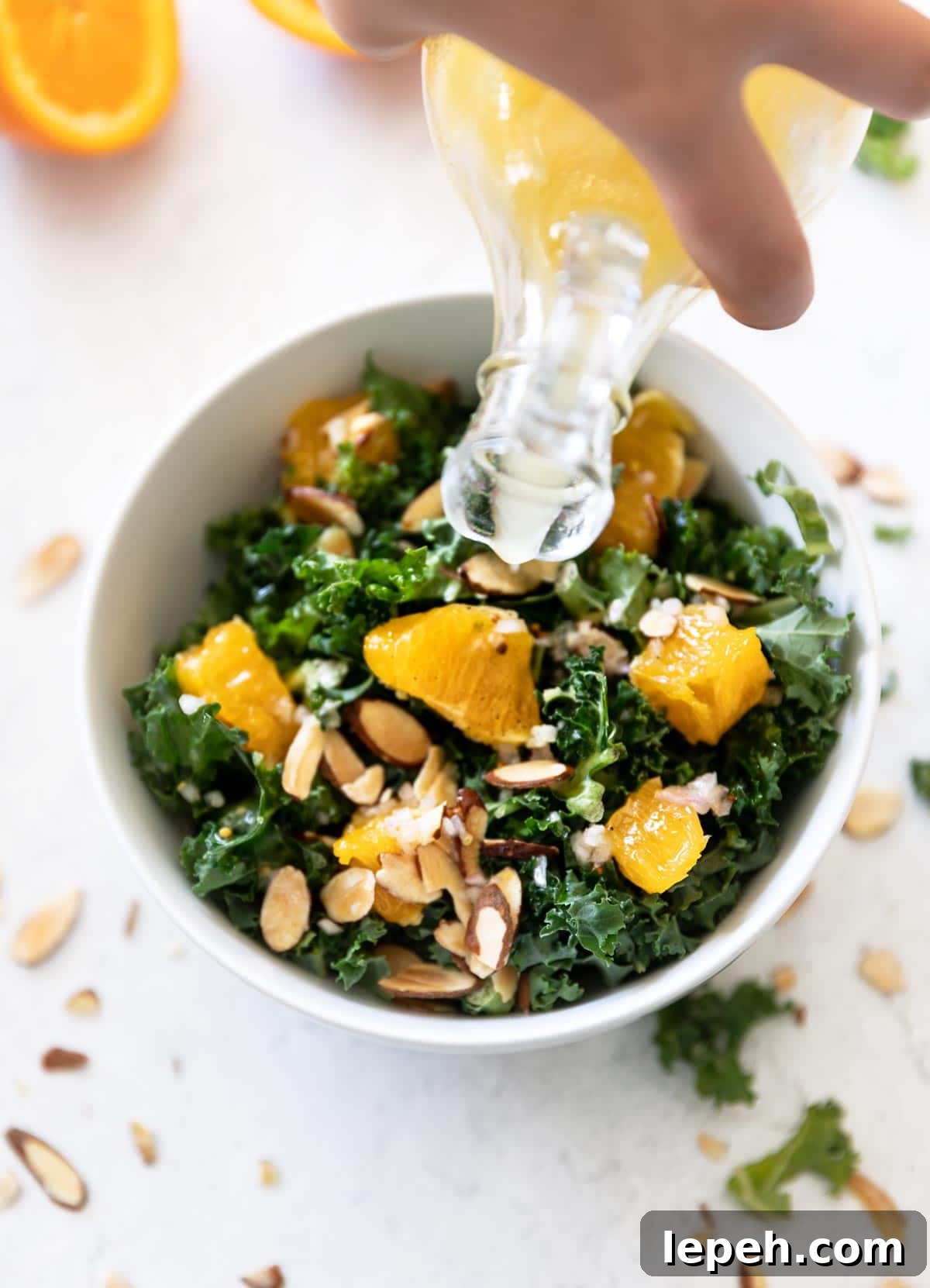 Person pouring dressing over naval orange salad.