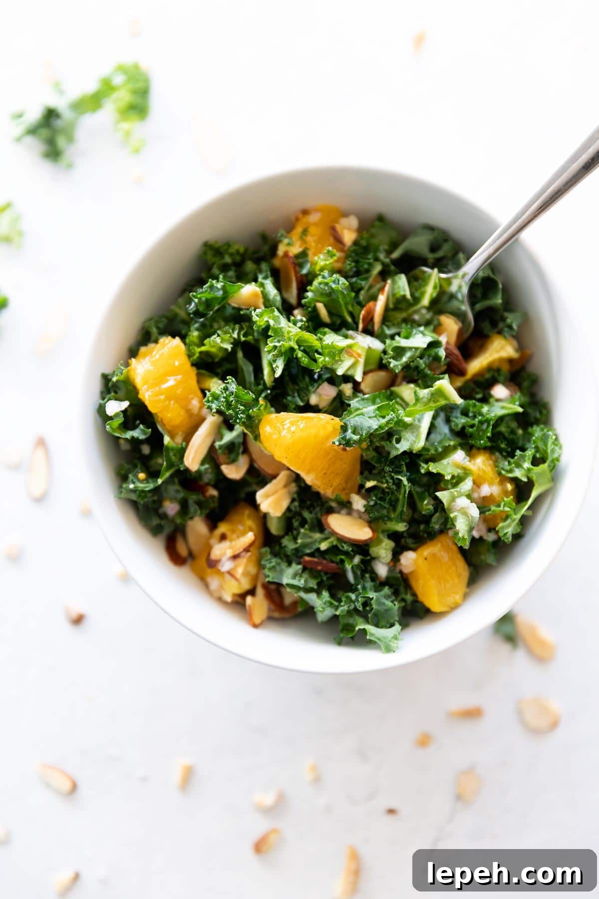 Fork in bowl of kale and orange salad.