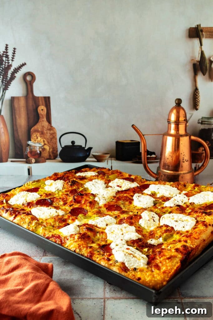 A whole grandma pizza in a dark gray metal pan on a cooling rack.