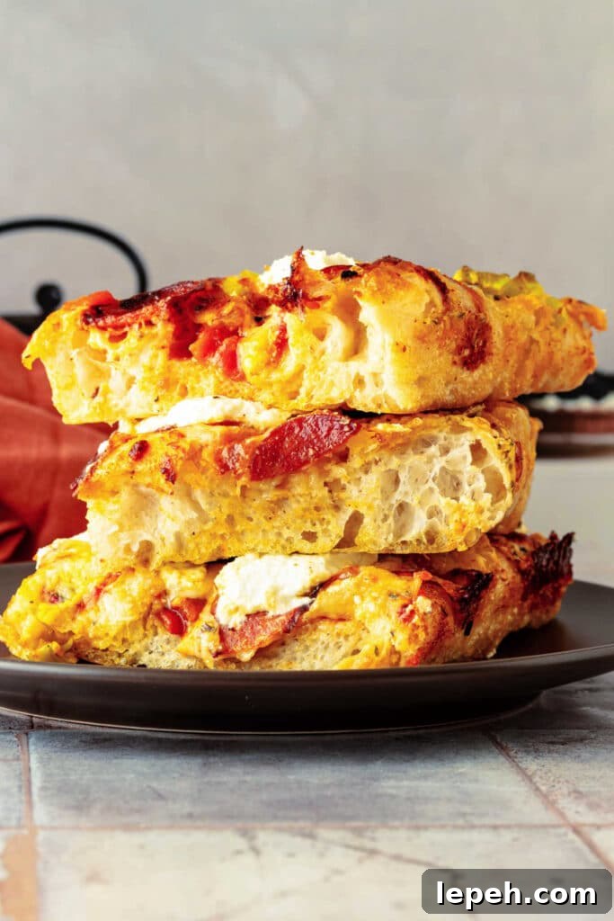 A stack of 3, airy, square pieces of grandma pizza on a brown plate.
