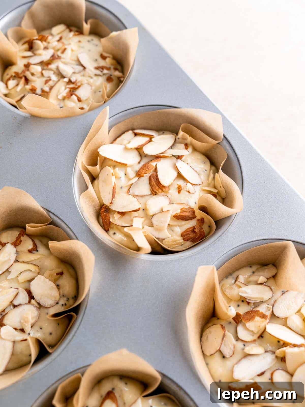 DIY muffin liners filled with almond poppy seed batter.
