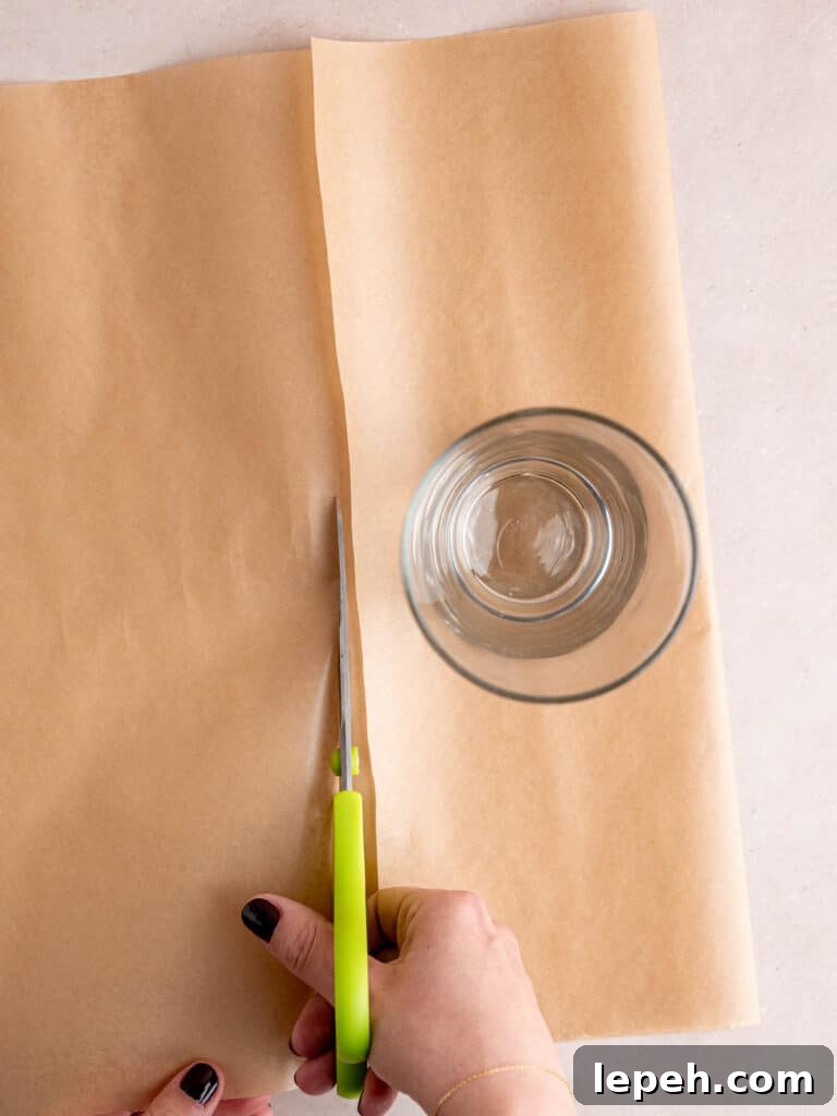 Cutting parchment paper to make cupcake liners.