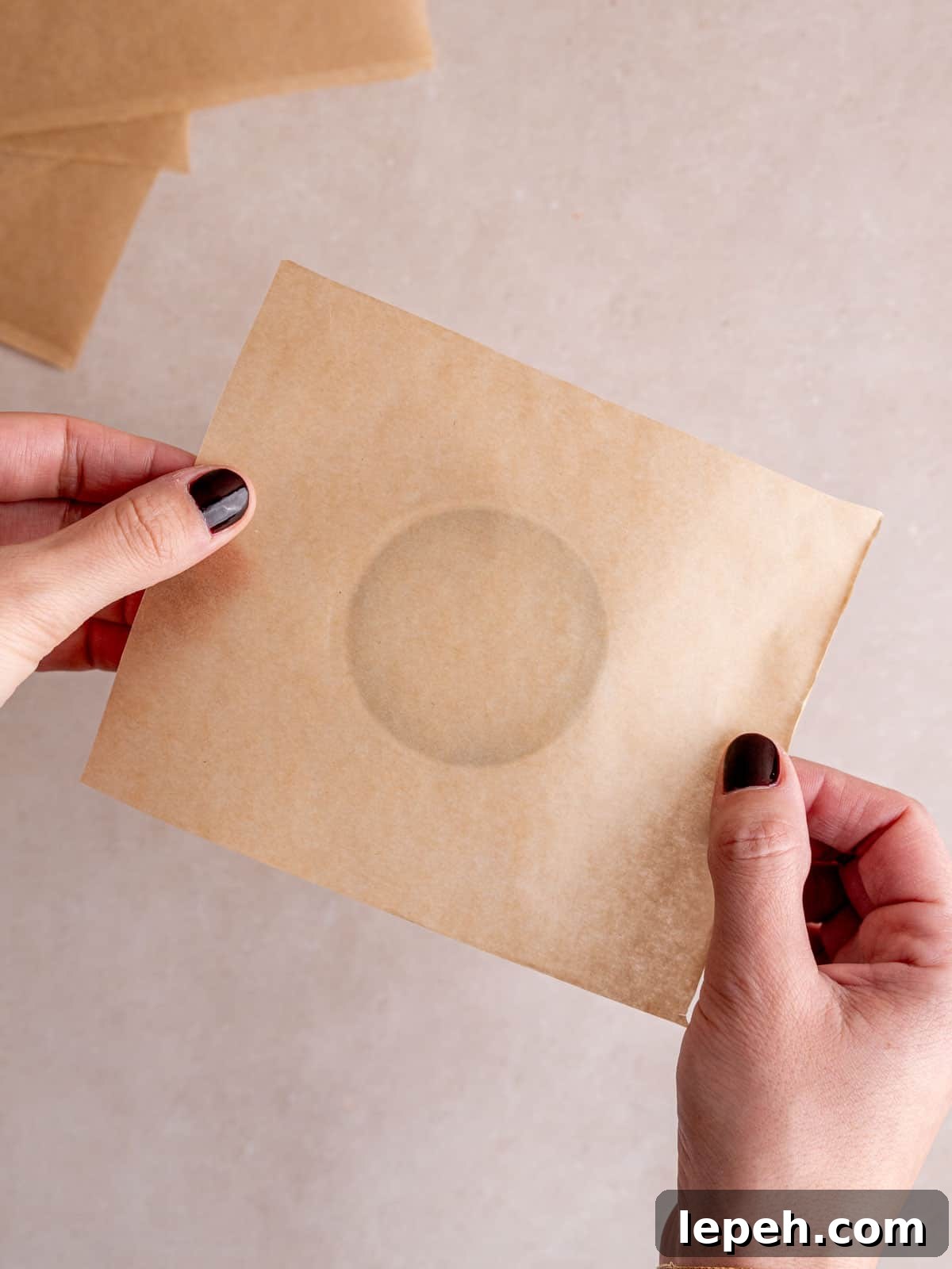 Holding a parchment paper square over the bottom of a pint glass.