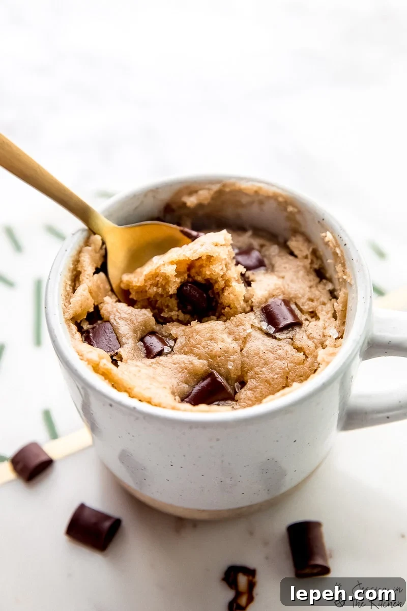 Close up of a spoon resting in a vegan chocolate chip mug cake.