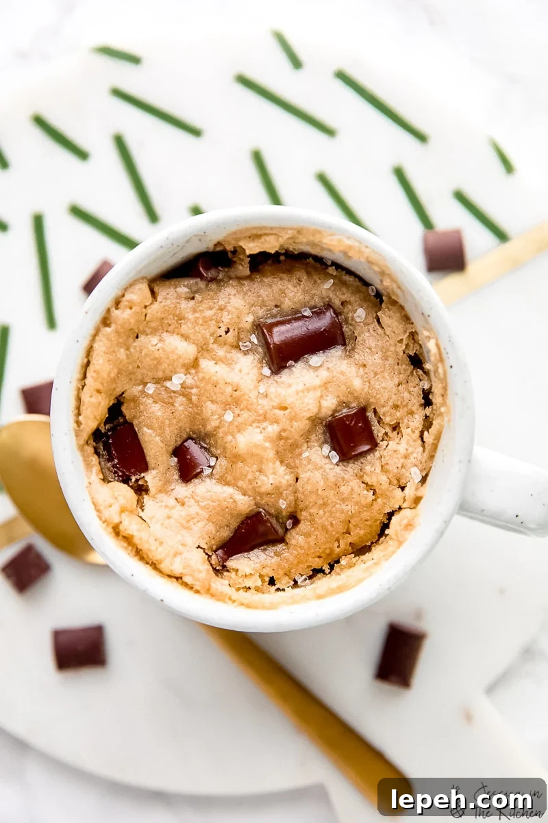 Overhead view of a chocolate chip mug cake next to a gold spoon.