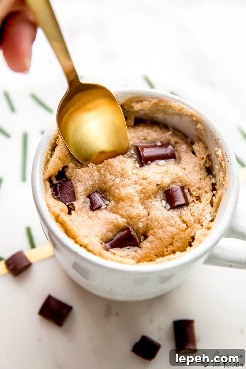 A spoon dipping into a vegan chocolate chip mug cake.