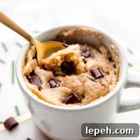Close up of a spoon resting in a vegan chocolate chip mug cake.