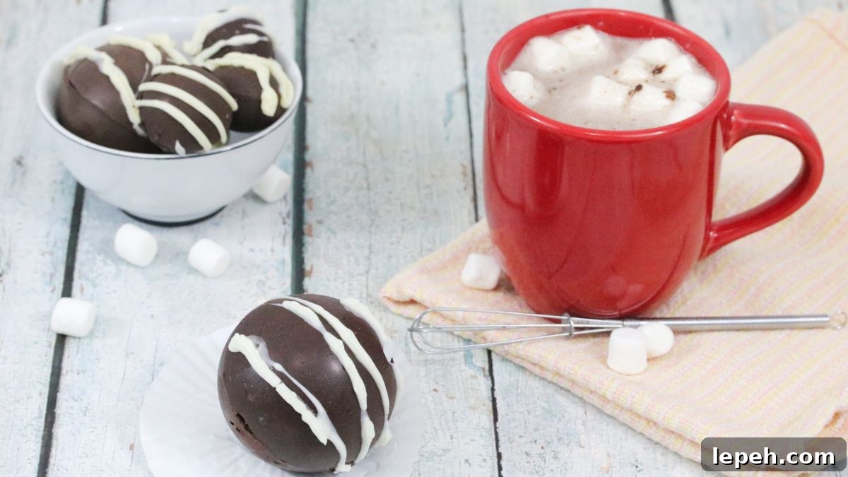 Hot chocolate bomb with white icing with a red cup of hot chocolate and marshmallows behind it.
