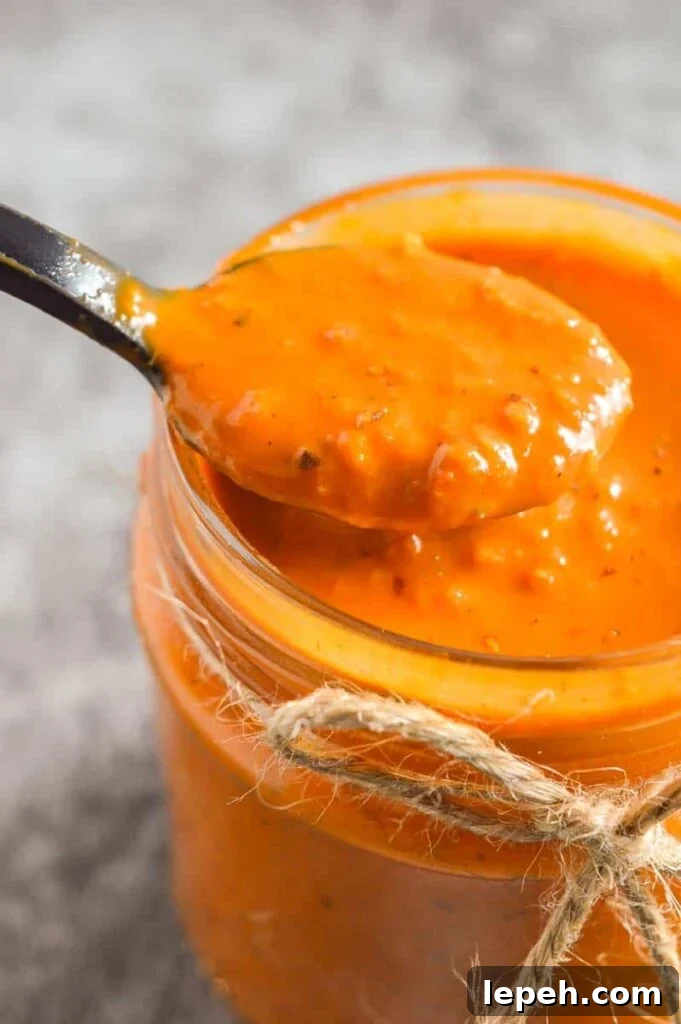 Closeup of a black spoon with slightly chunky orange sauce