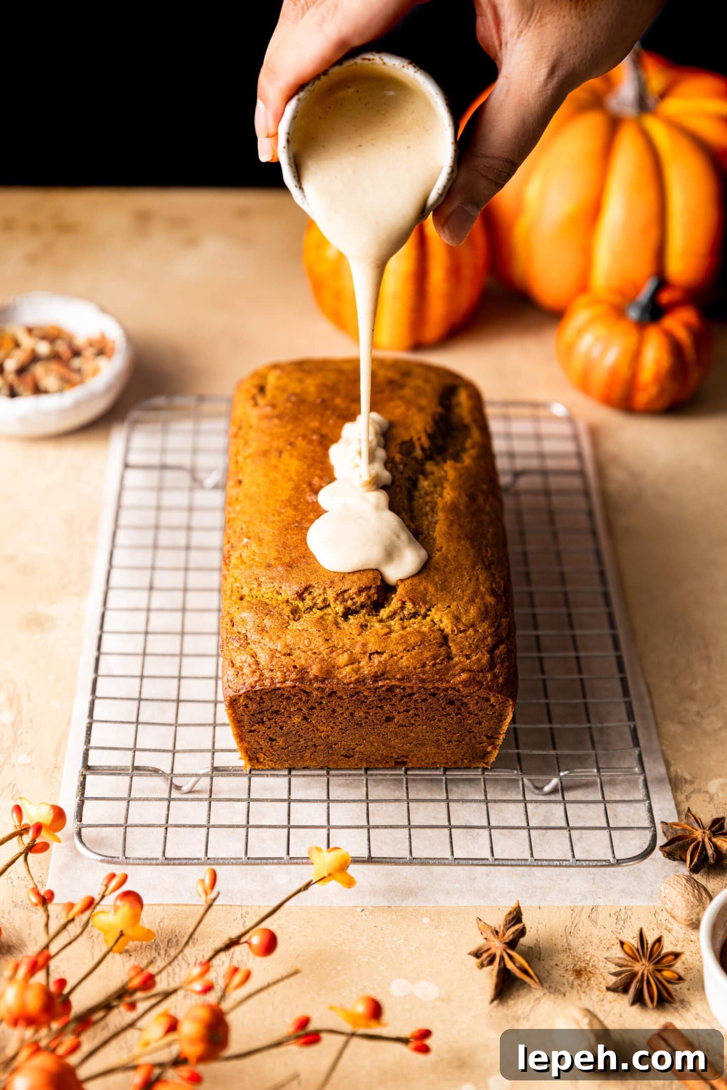 Maple glaze being poured on top of pumpkin bread loaf