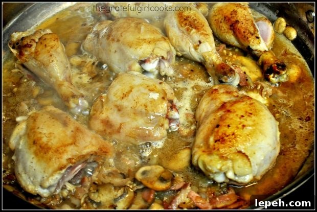 Chicken, onions, garlic are added back into coq au vin sauce.