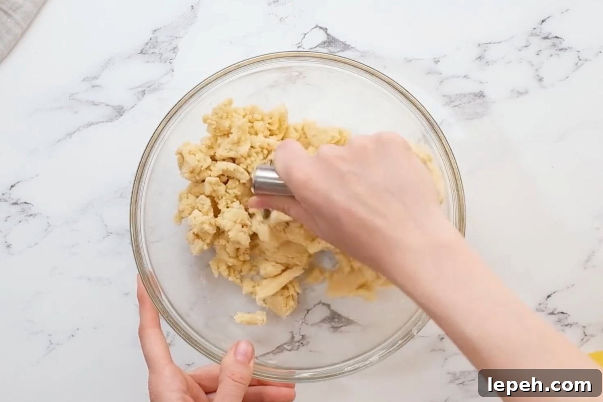 mixing shortbread crust in a glass bowl with a pastry cutter.
