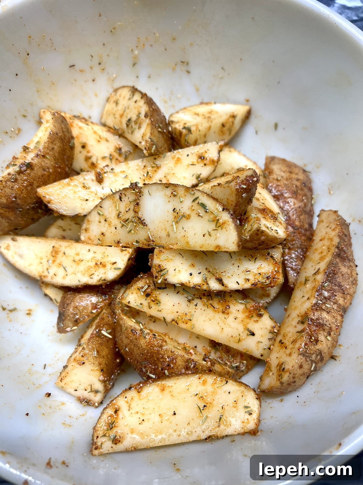 Bowl of potato wedges with seasonings.
