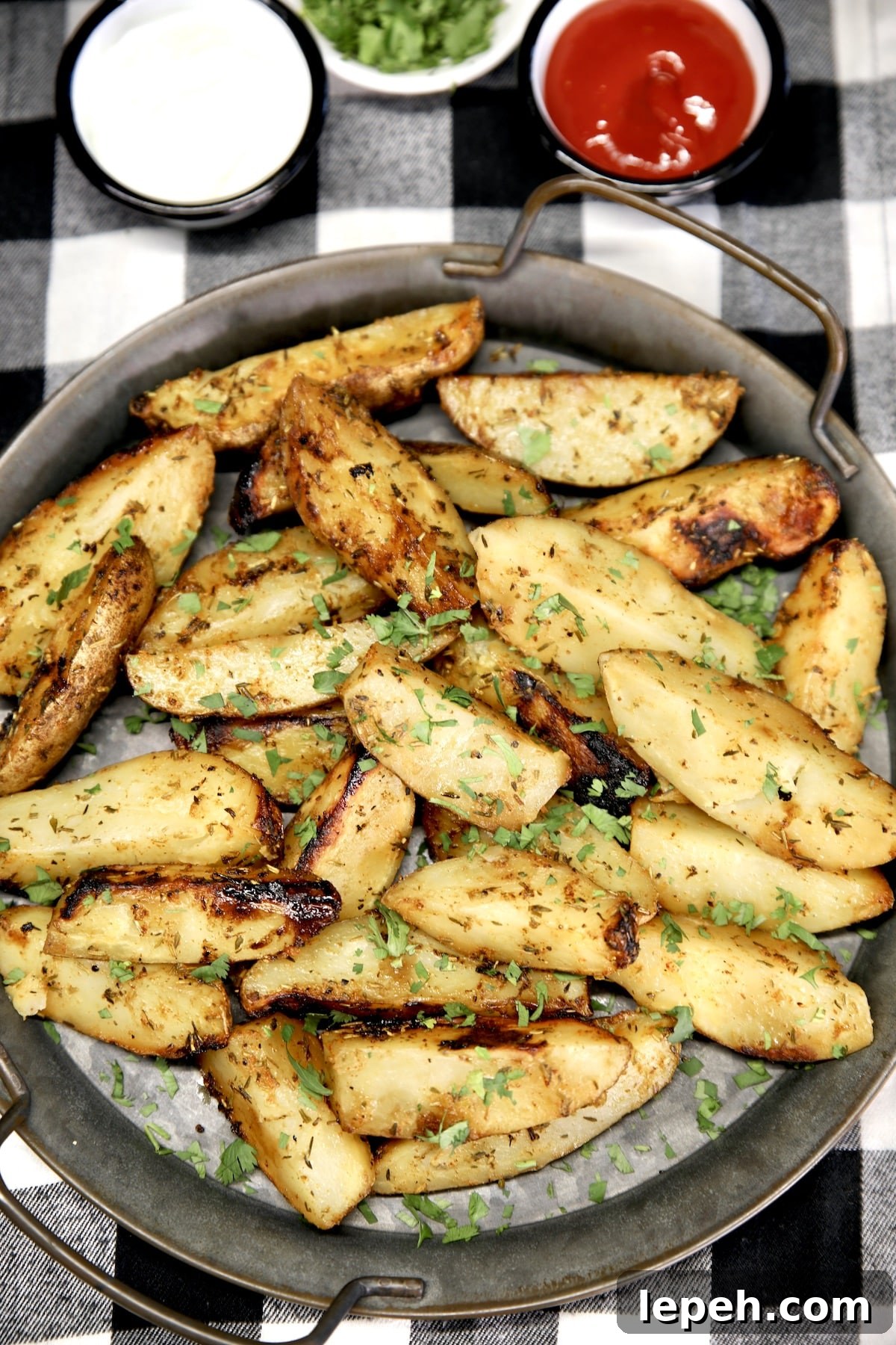 Potato wedges on a platter, bowls of dipping sauces.