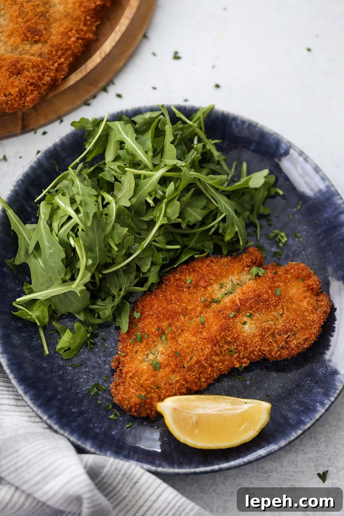 chicken milanese with a lemon wedge and arugula on the side.